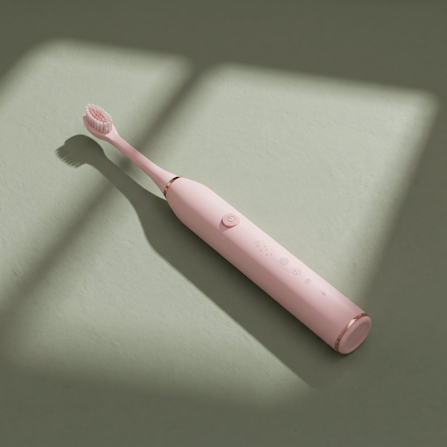 Pink OralCove electric toothbrush placed diagonally on a muted sage background.